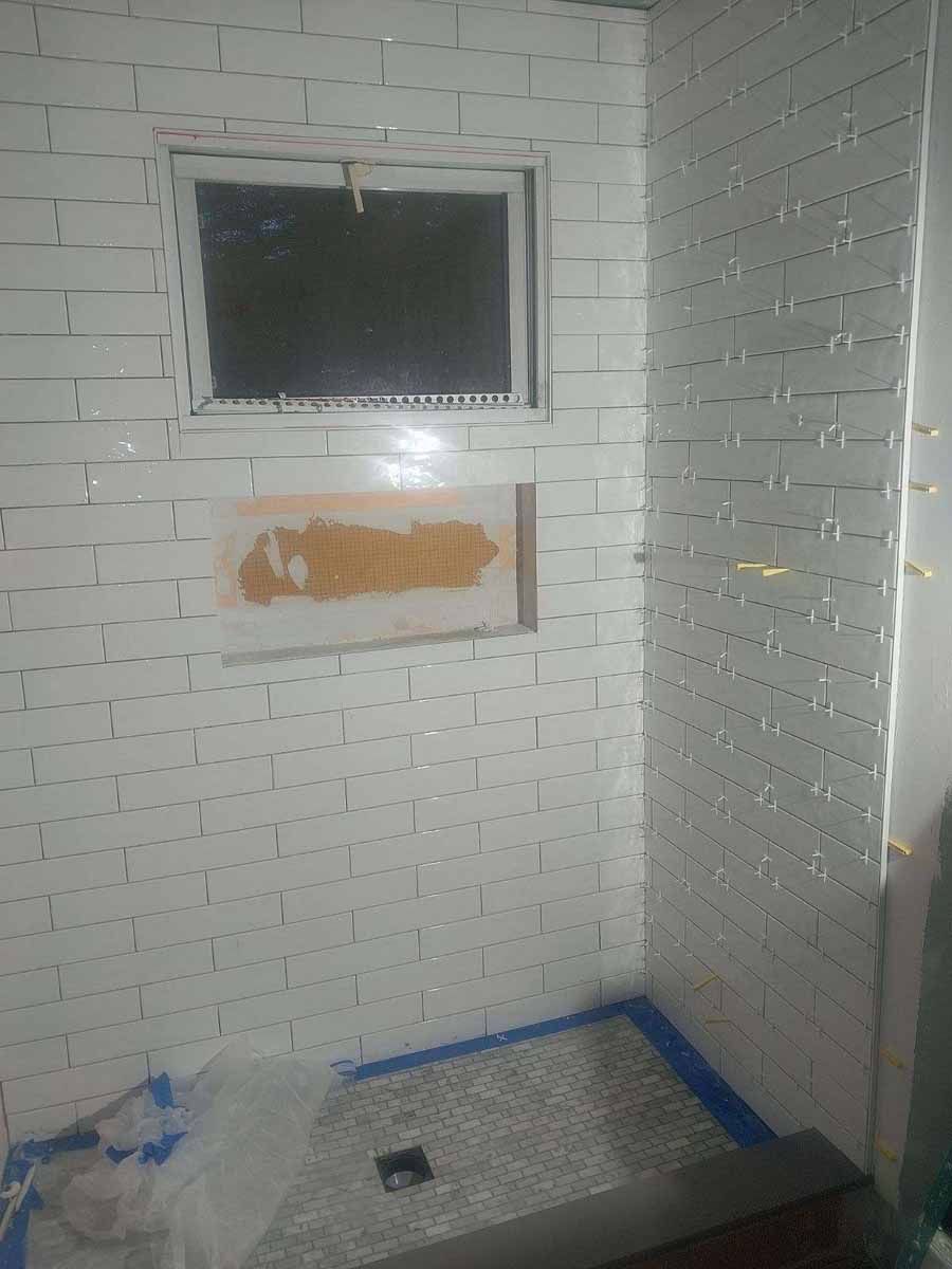 Bathroom with white subway tiles, a small window, and a pebble-tiled shower floor.