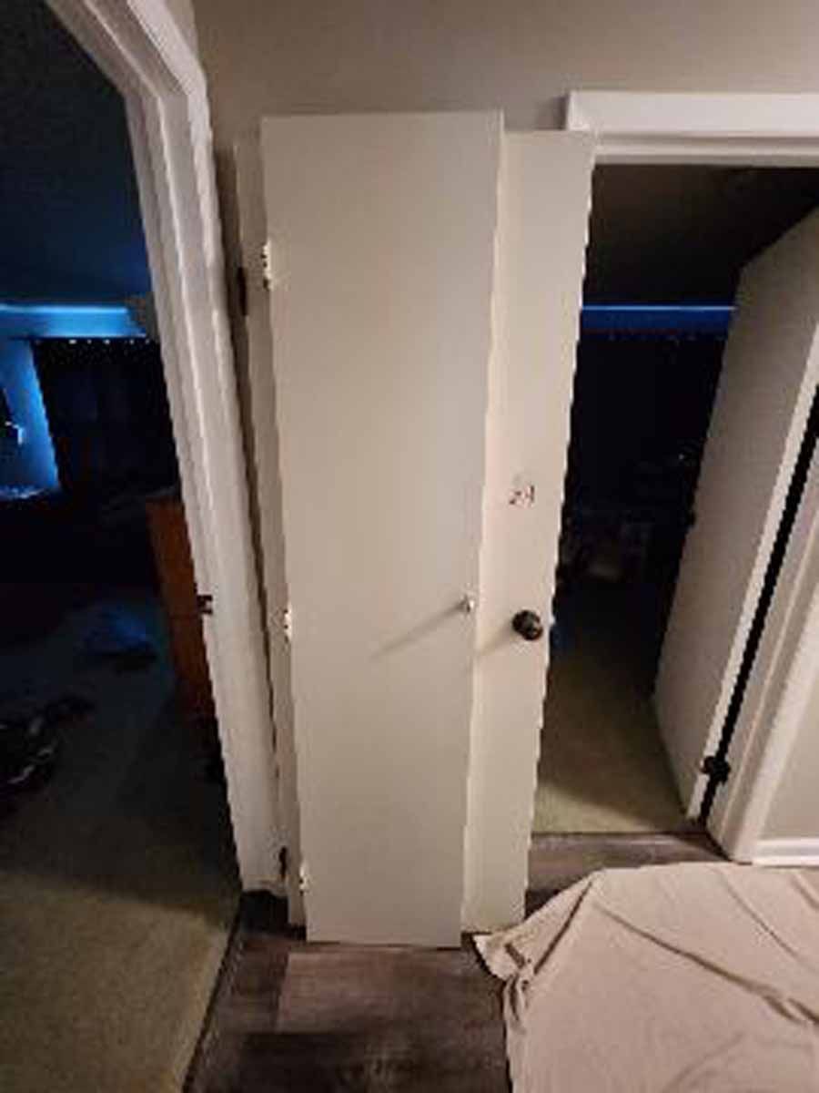 A partially open white door in a doorway, showing a dark room on each side.