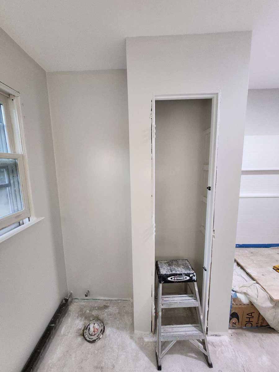 Interior wall with alcove, unfinished renovation. Small stepladder inside the alcove. Pale walls, window visible.