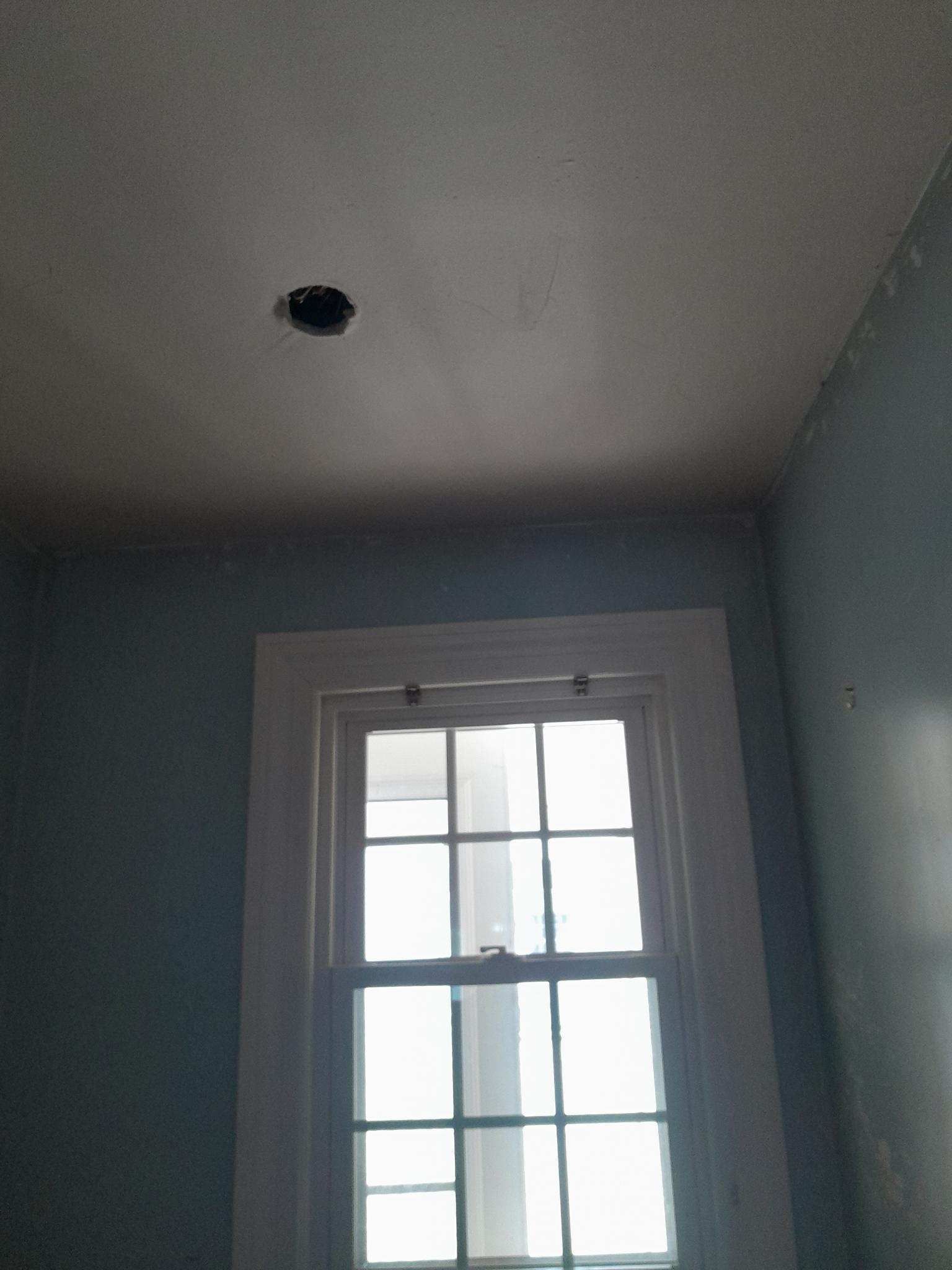 Window with white trim and a ceiling light fixture against a blue-green wall.