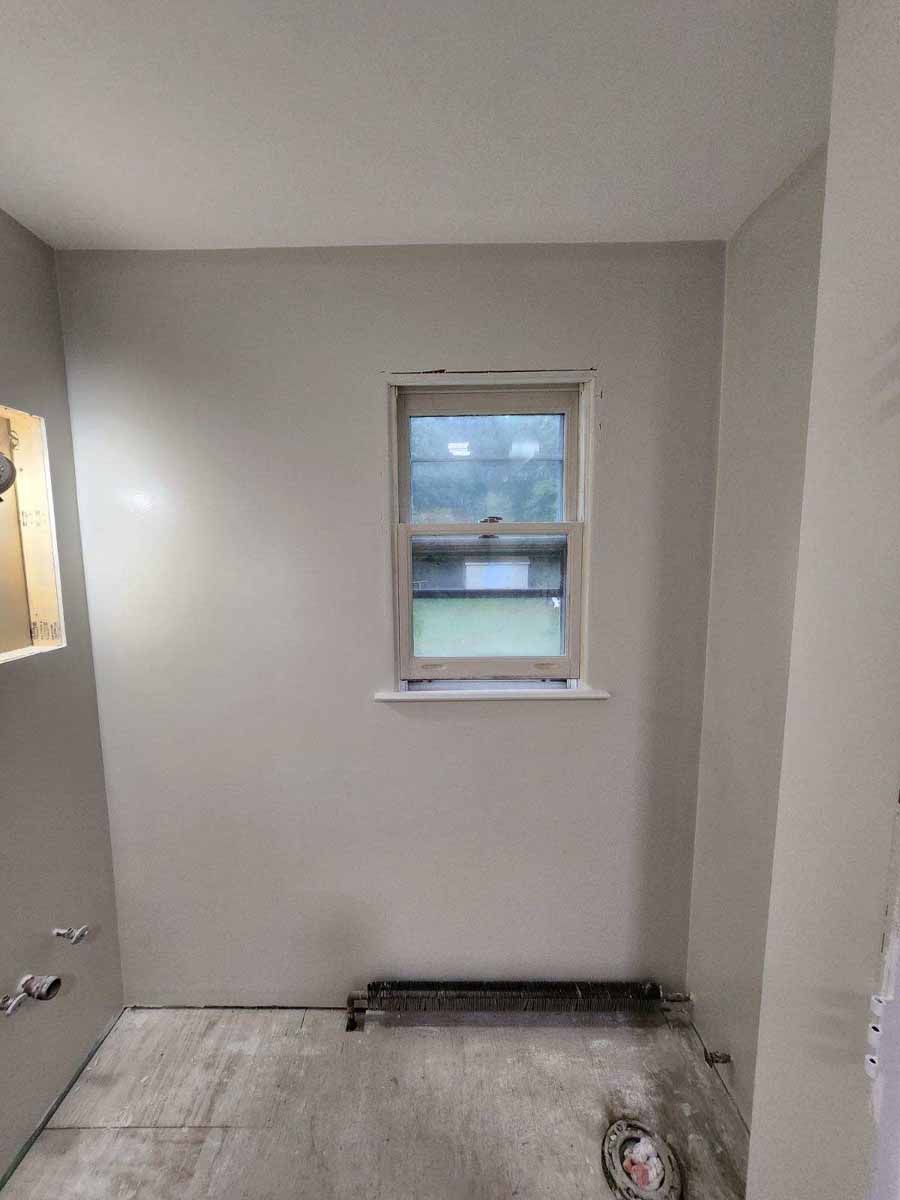 Bathroom interior with a window and unfinished surfaces.