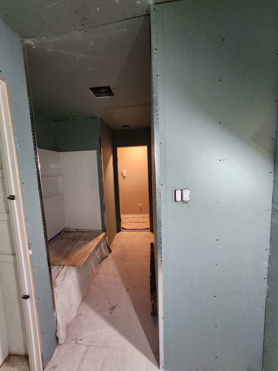 Interior hallway under construction; walls are painted blue-grey, unfinished drywall.