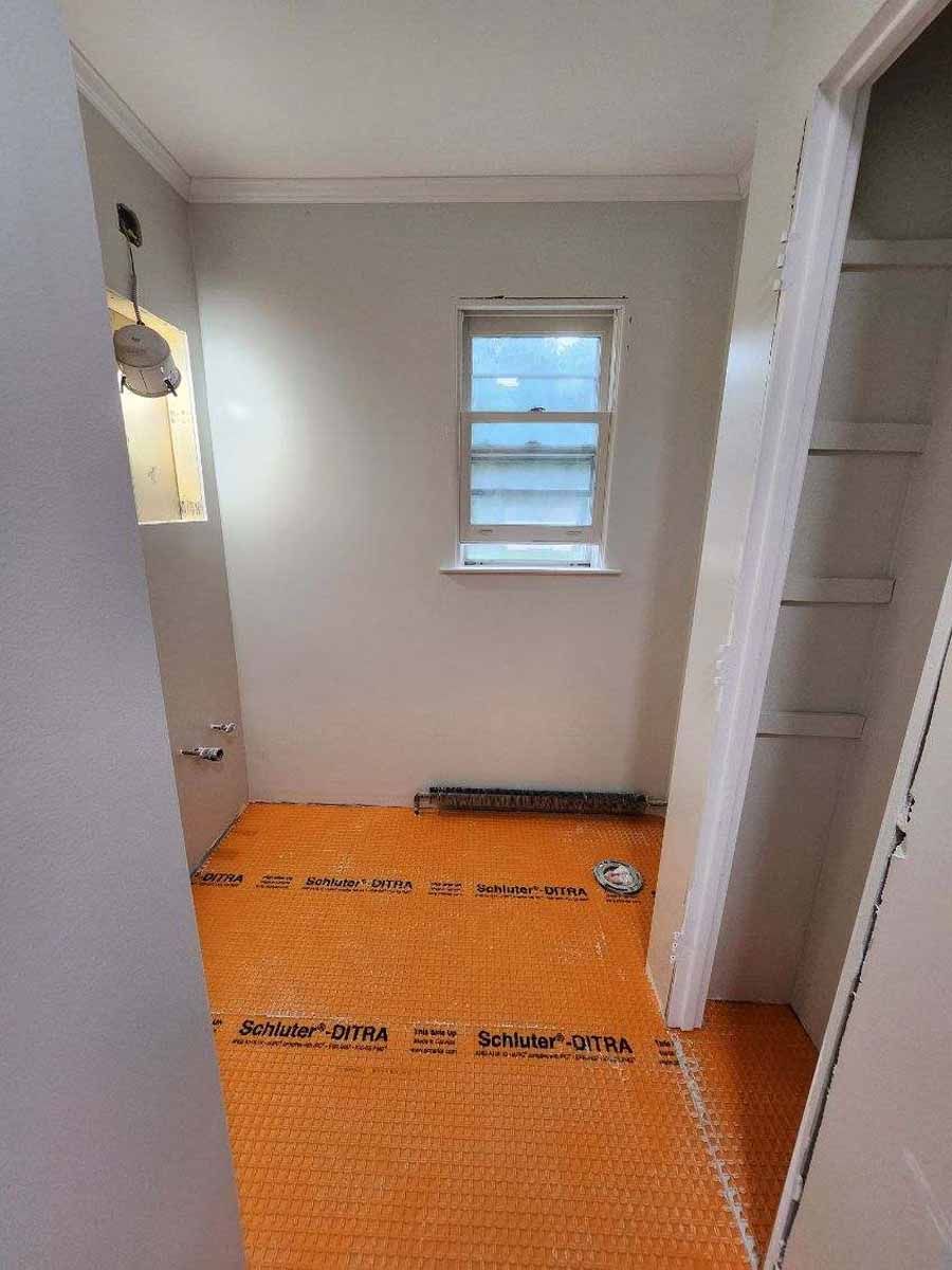 Bathroom under construction with orange subfloor, small window, and open closet.