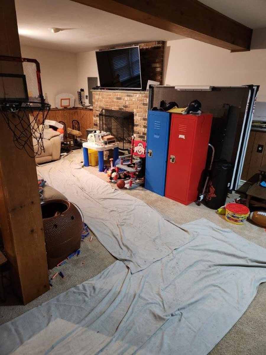 Basement with a fireplace, TV, lockers, and play area, covered with a gray sheet.