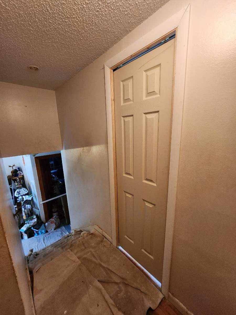 Interior doorway leading to a staircase, with a closed six-panel door and white trim.