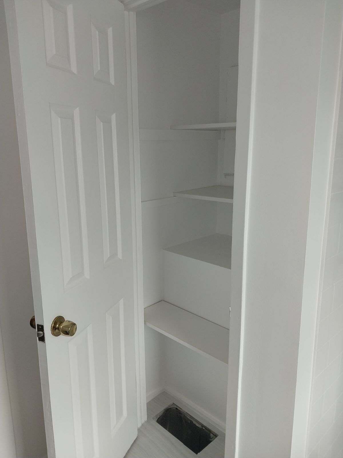 White closet door open, showing white shelves. A floor vent is visible.