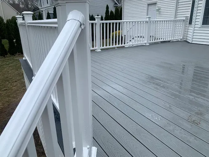 White railing on a gray composite deck, with a house in the background.