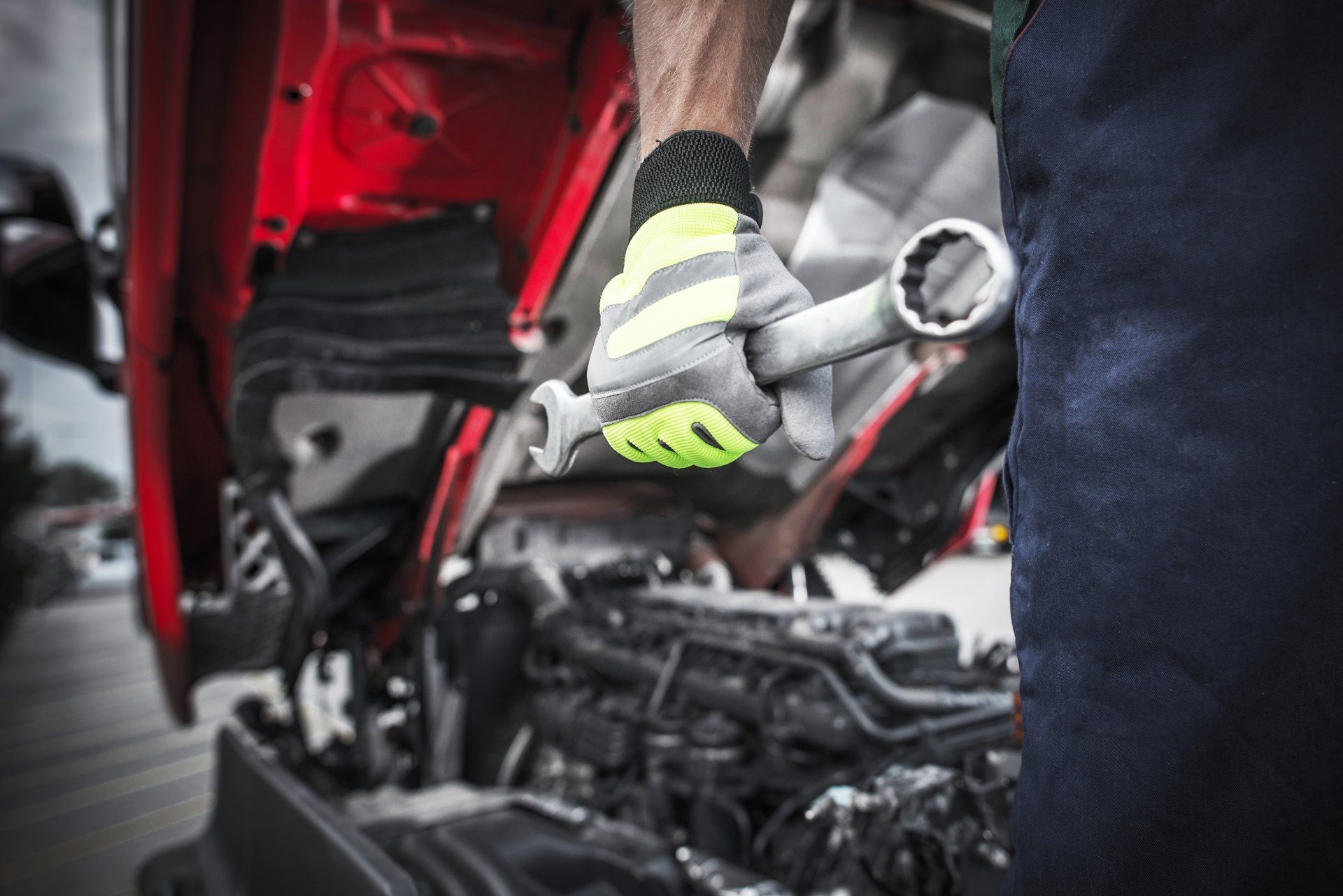 A man is working on a truck engine with a wrench.