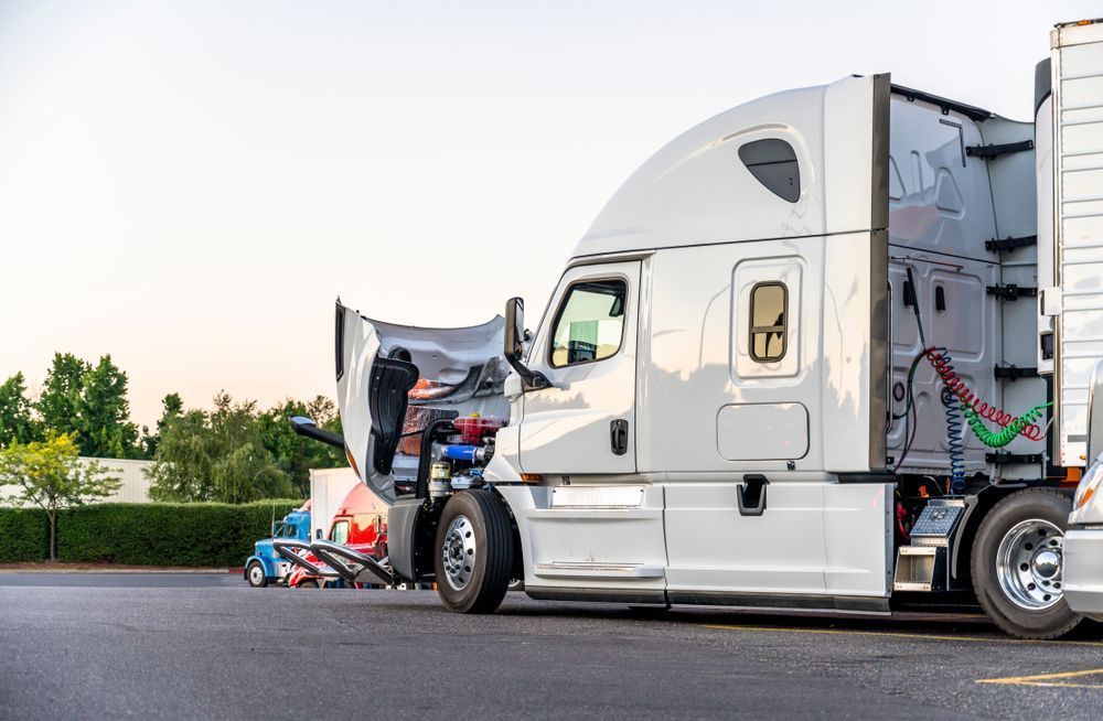 A semi truck with its hood open is parked in a parking lot.