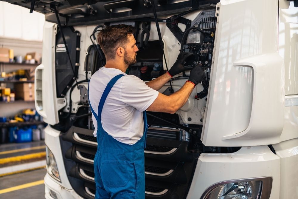 A man is working on the engine of a truck in a garage.