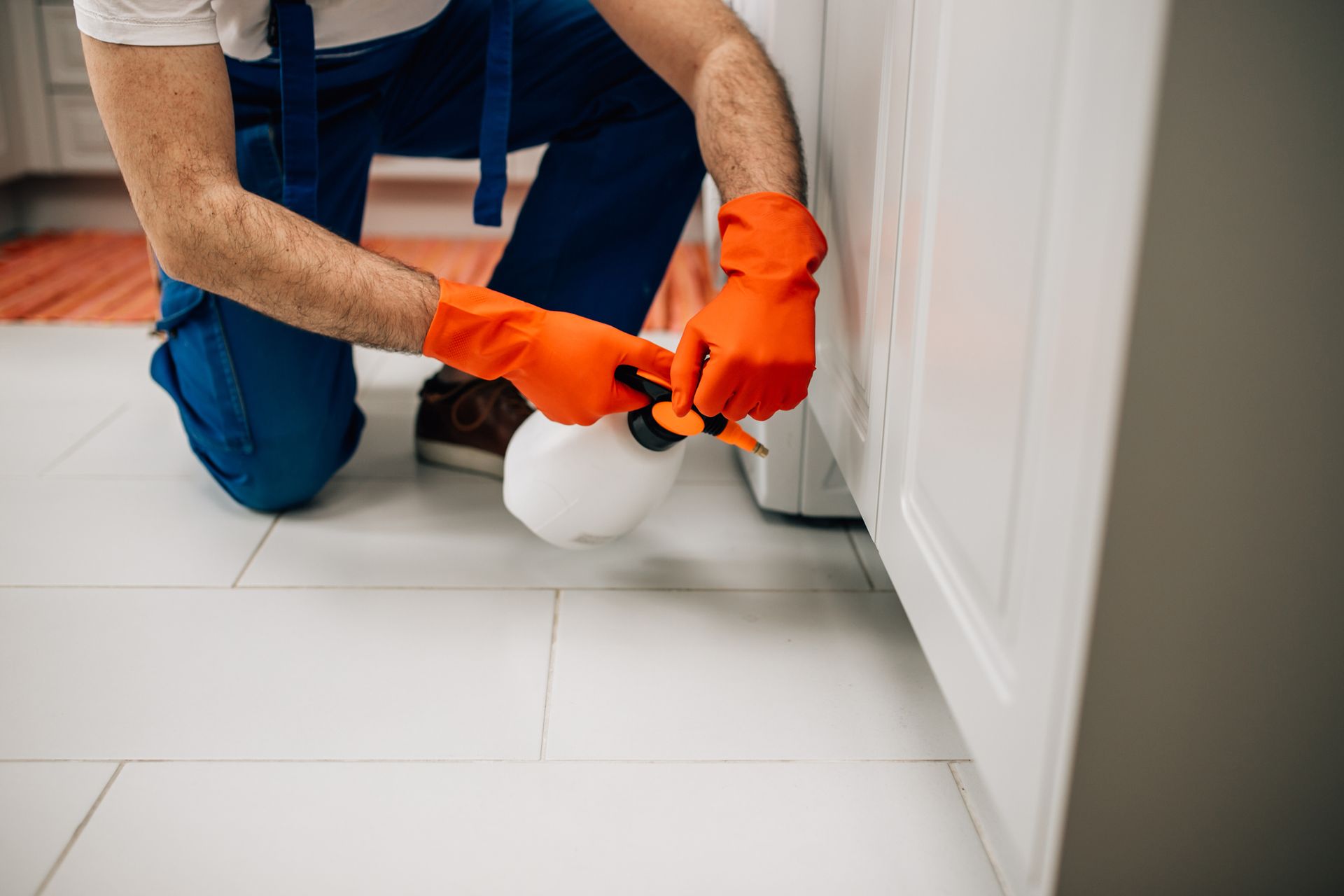 A man in a protective suit is spraying a room with a sprayer.