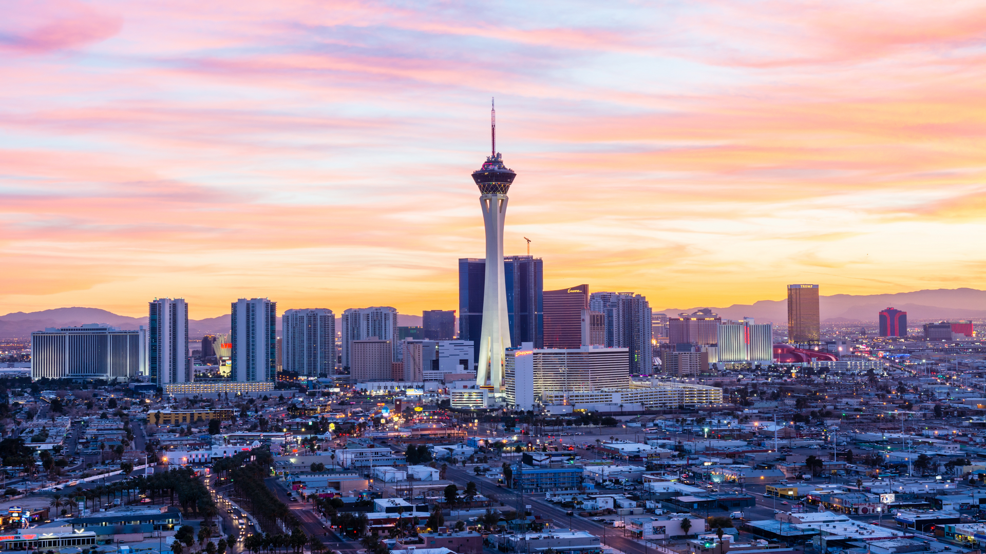 An aerial view of las vegas skyline at sunset with the stratosphere tower in the foreground.