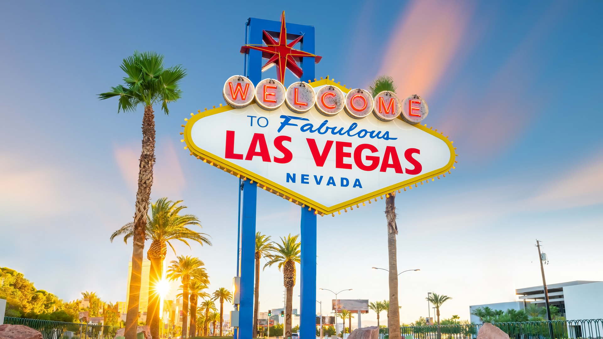 A large welcome to las vegas sign with palm trees in the background.