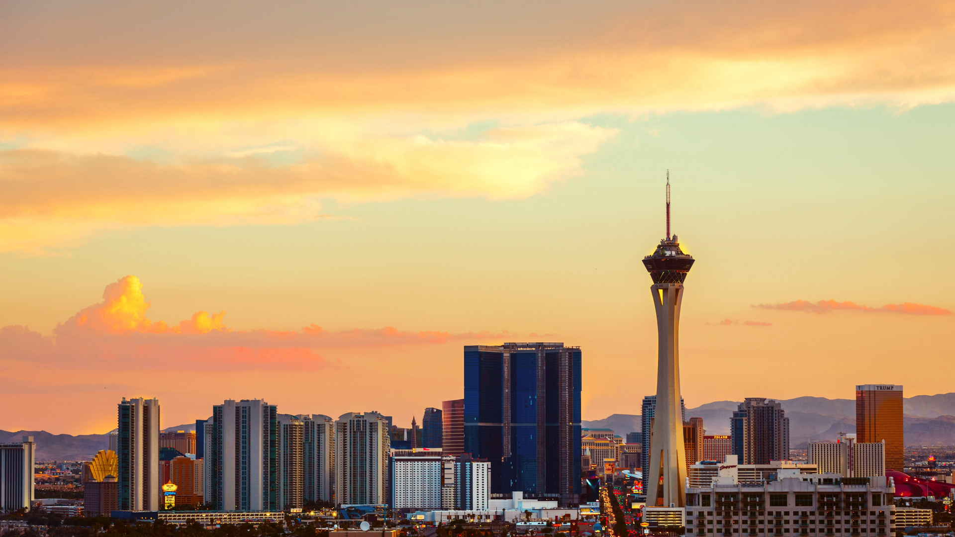 A city skyline at sunset with a clock tower in the foreground.