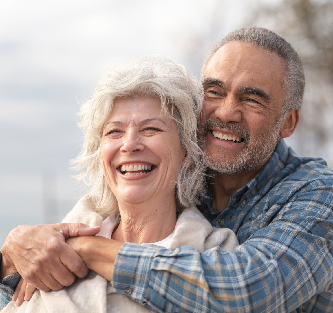 A man and a woman are hugging each other and smiling.