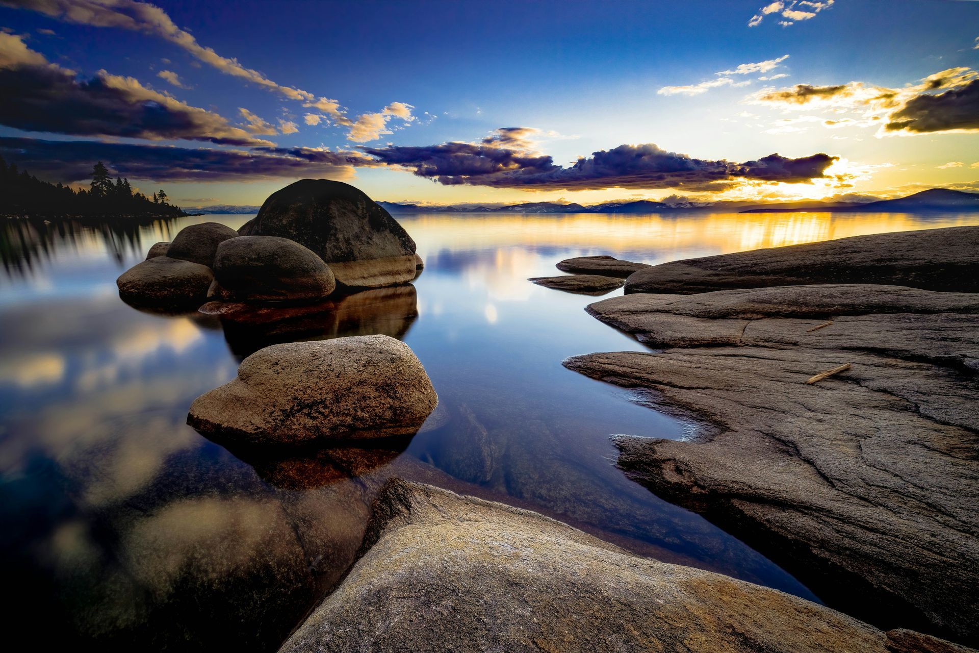 A sunset over a lake with rocks in the water