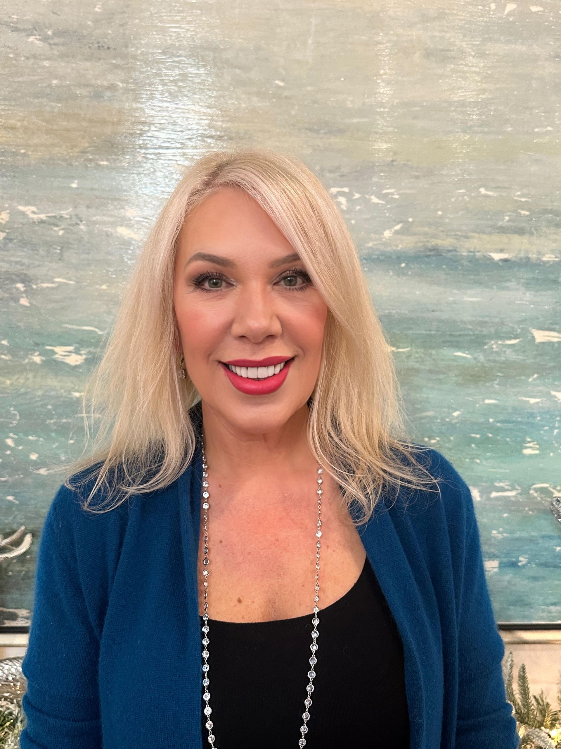 A woman with blonde hair and red lipstick is smiling for the camera.