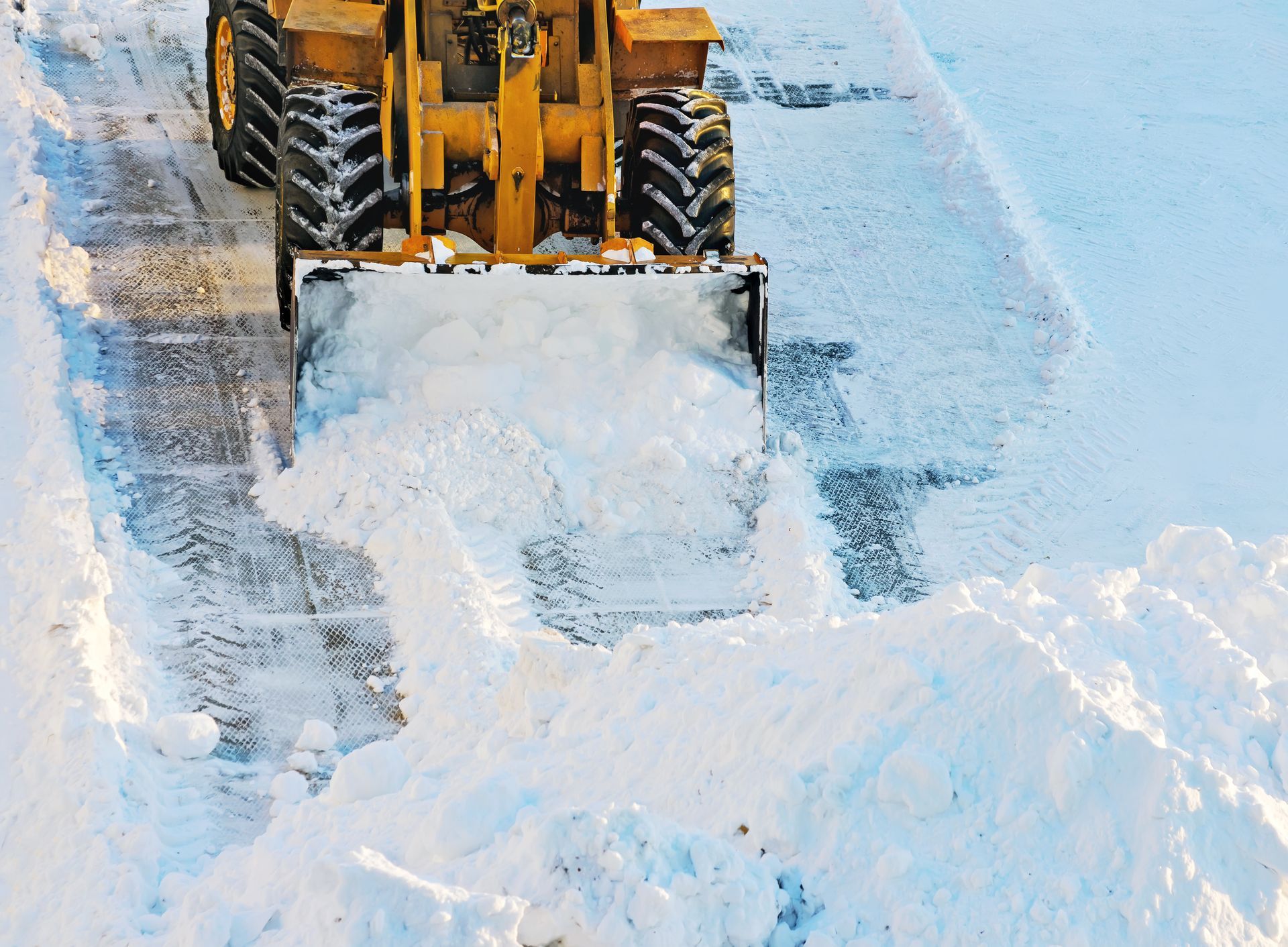 A man in a blue and orange jacket is shoveling snow.