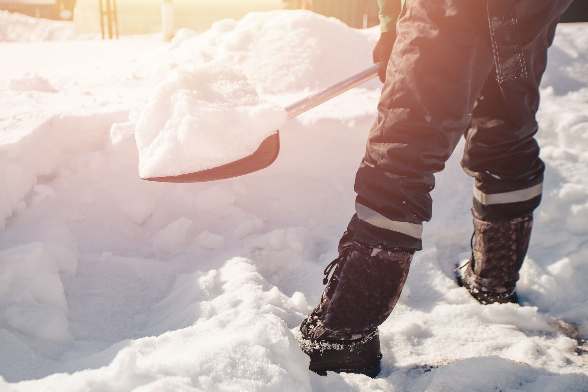 A person is shoveling snow from the ground with a shovel.