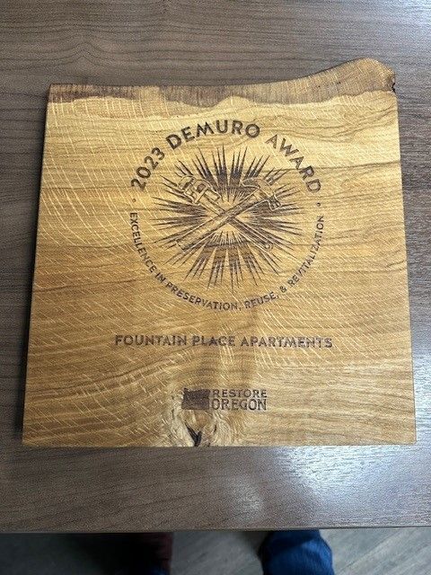 Wooden plaque for the 2023 Demuro Award for historic preservation. Fountain Place Apartments. Restore Oregon logo.