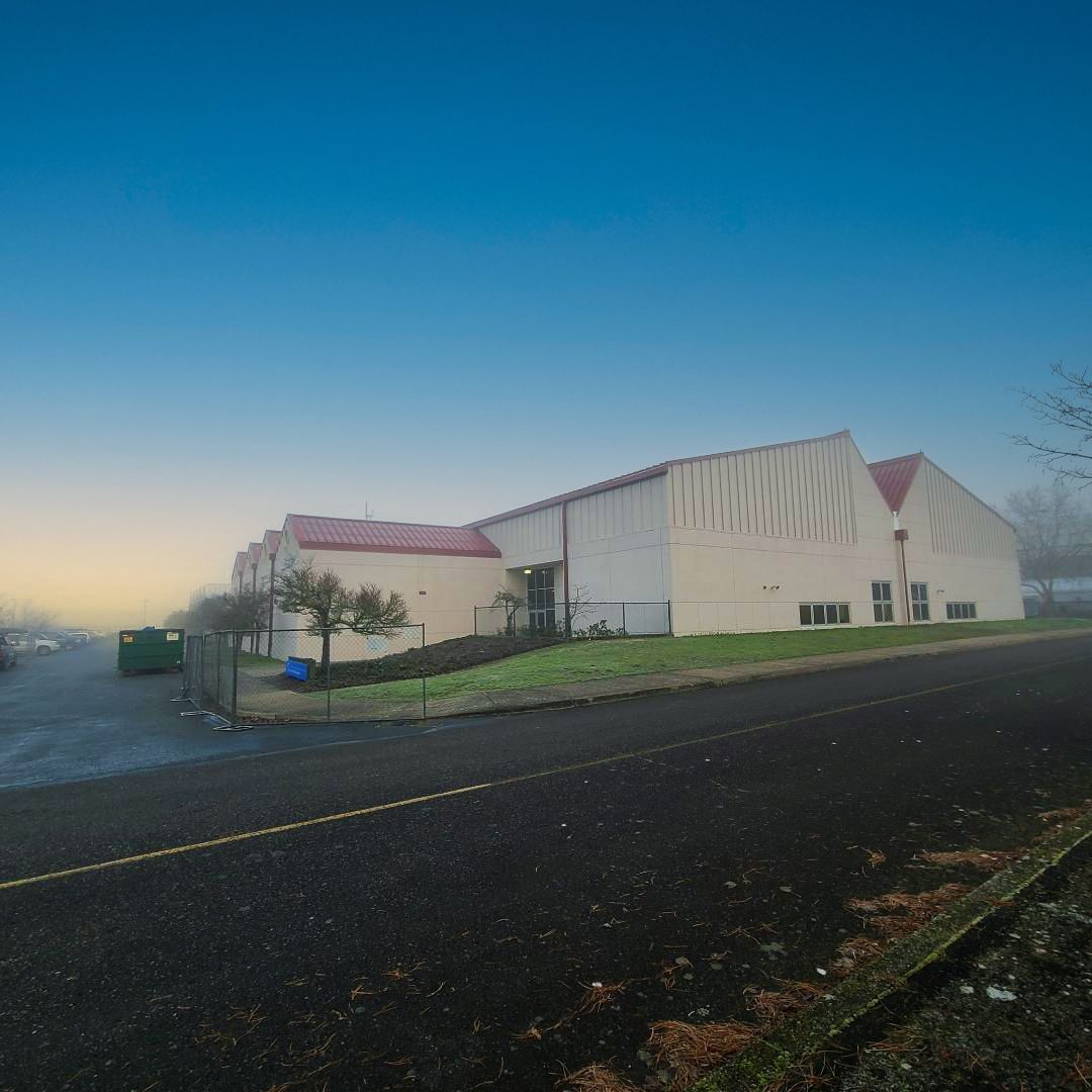 A building with a red roof on a foggy day. The building is beige with a paved road in the foreground.