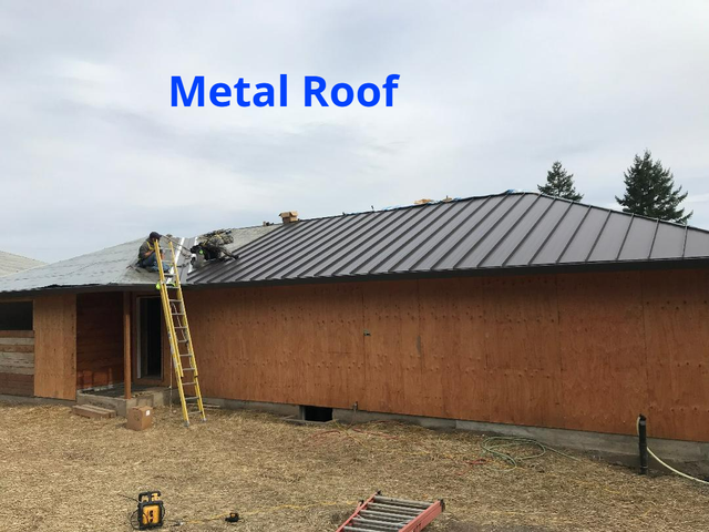Metal roof being installed on a building, construction workers on roof, a ladder is present.