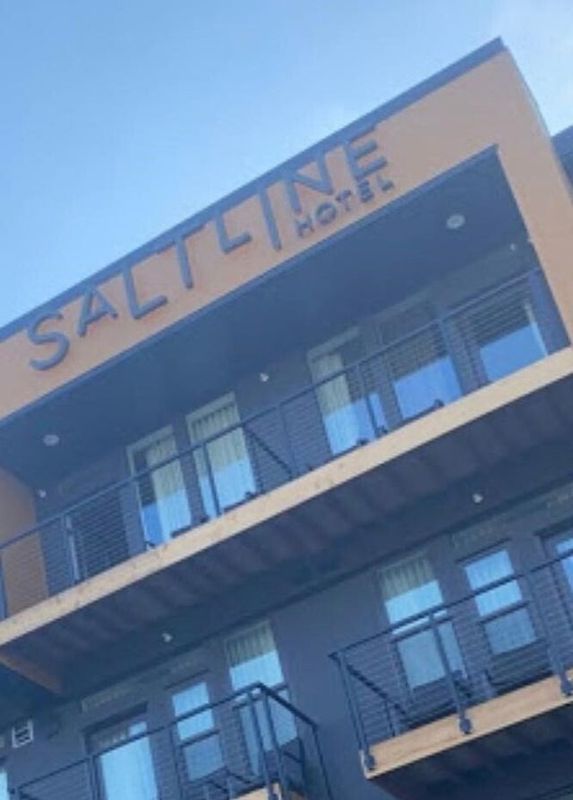 Saltline Hotel exterior, modern building with balconies, blue sky overhead.
