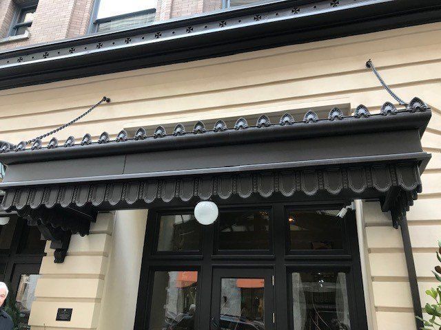 Black awning over a storefront entrance with a decorative scalloped edge.