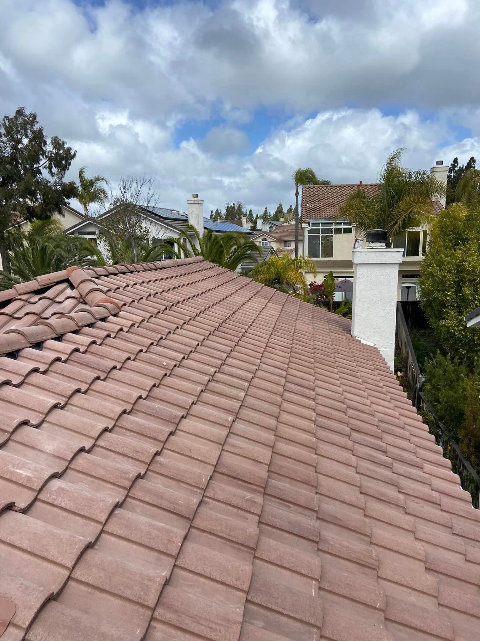 The roof of a house with a tiled roof and a chimney.