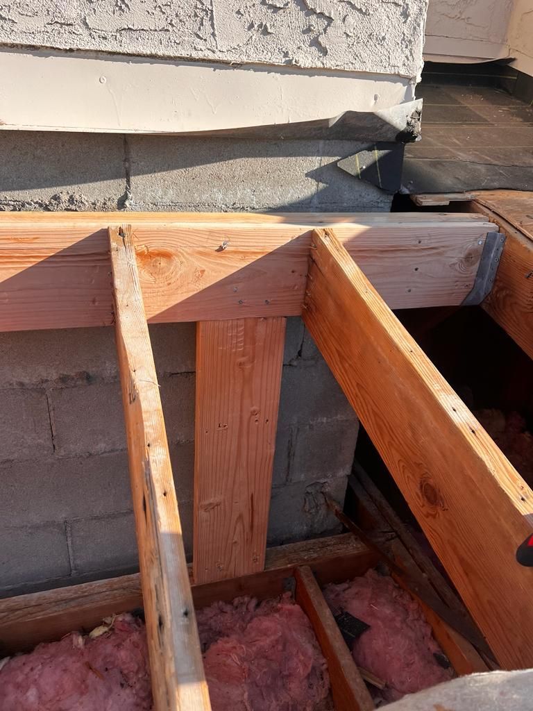 A wooden structure is being built on top of a brick wall.