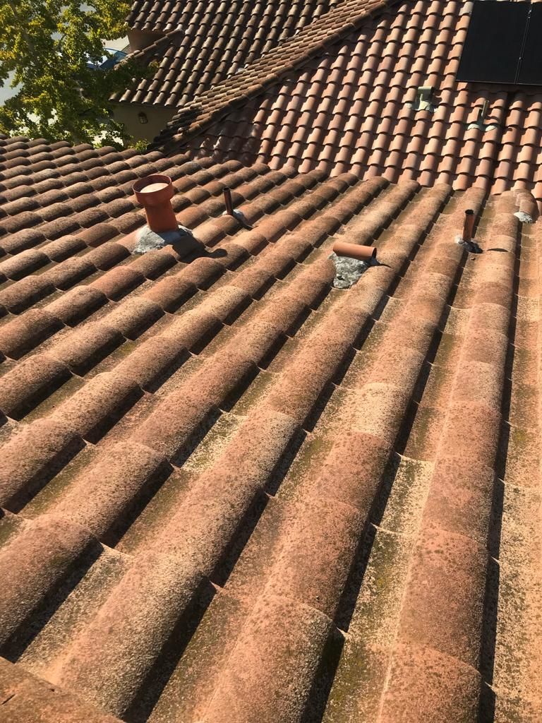A close up of a tiled roof with a chimney on top of it.