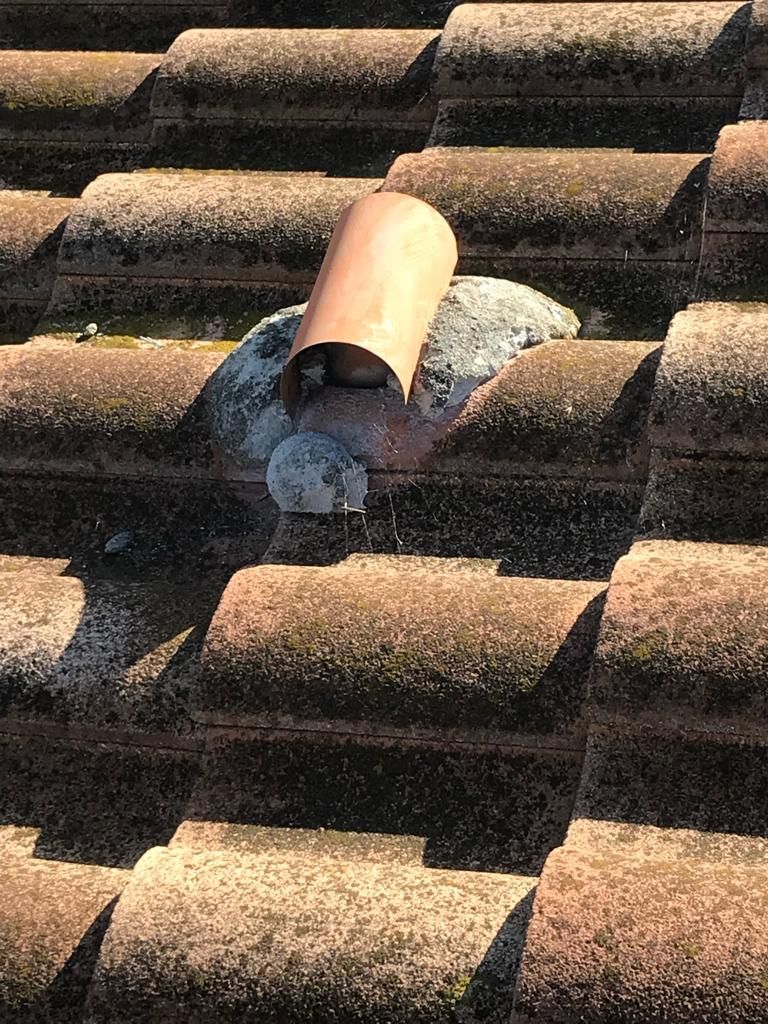 A close up of a tiled roof with a hole in it.