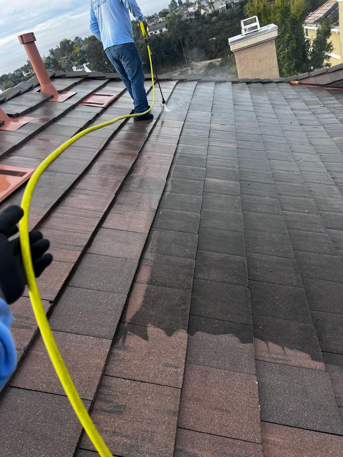 A person is cleaning a roof with a hose.
