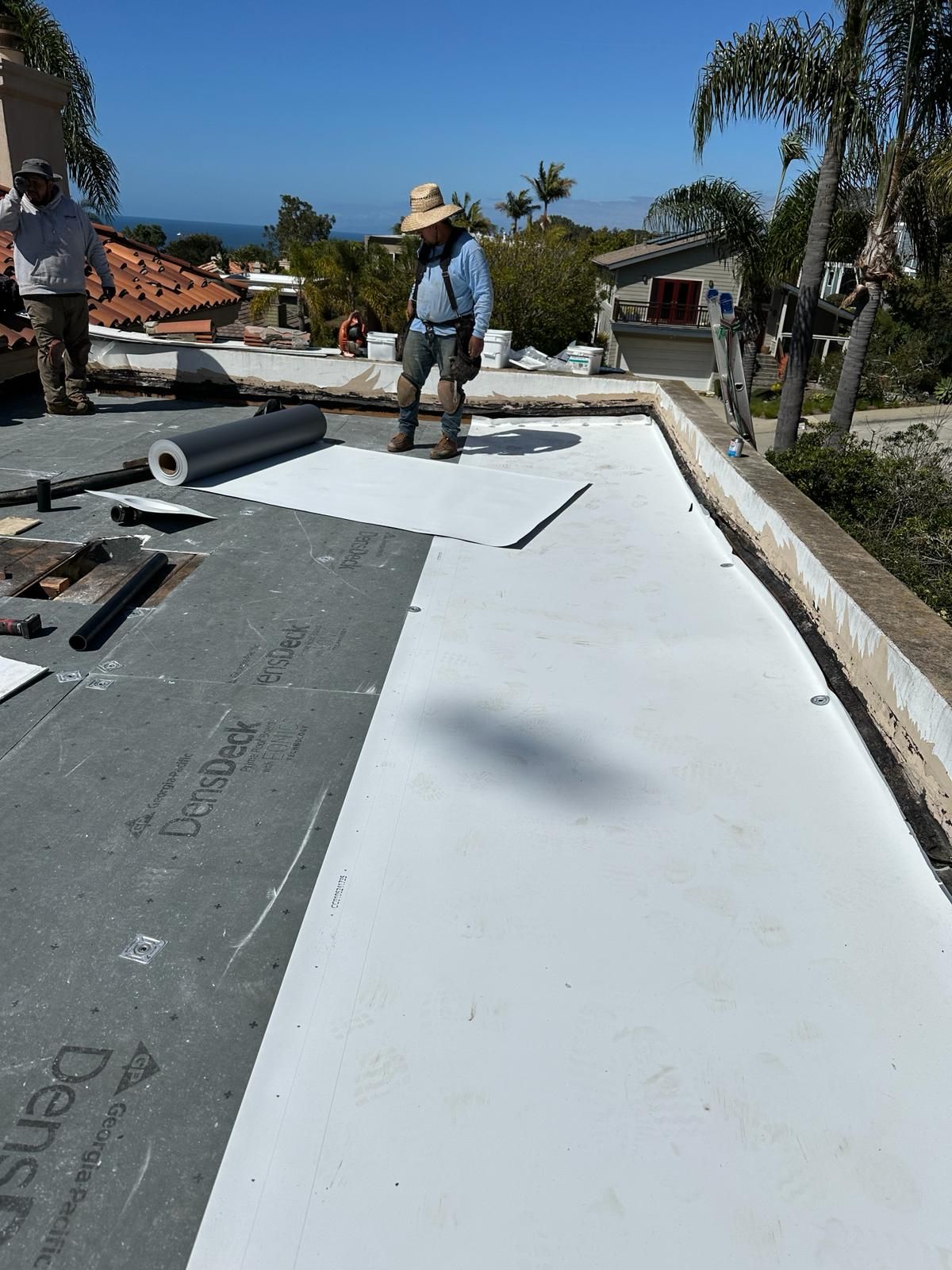 A man in a hat is standing on a white roof