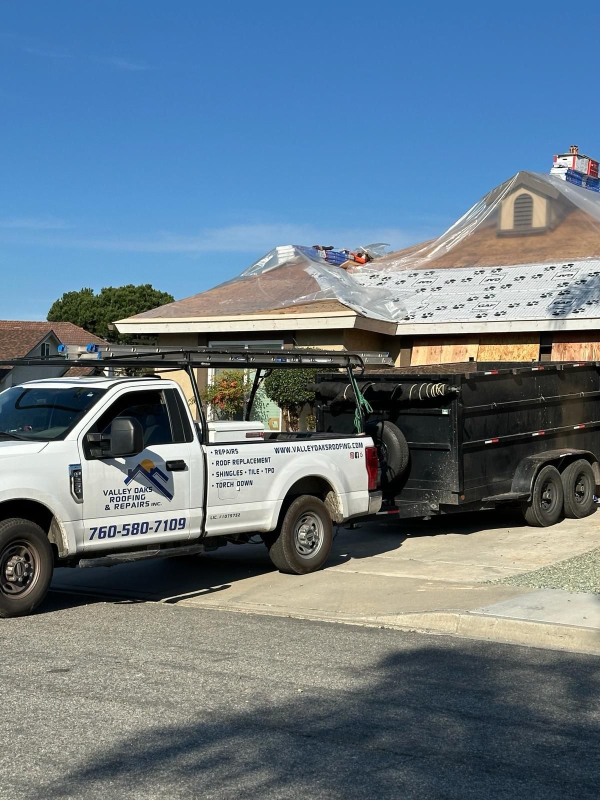 A truck with a trailer attached to it is parked in front of a house.