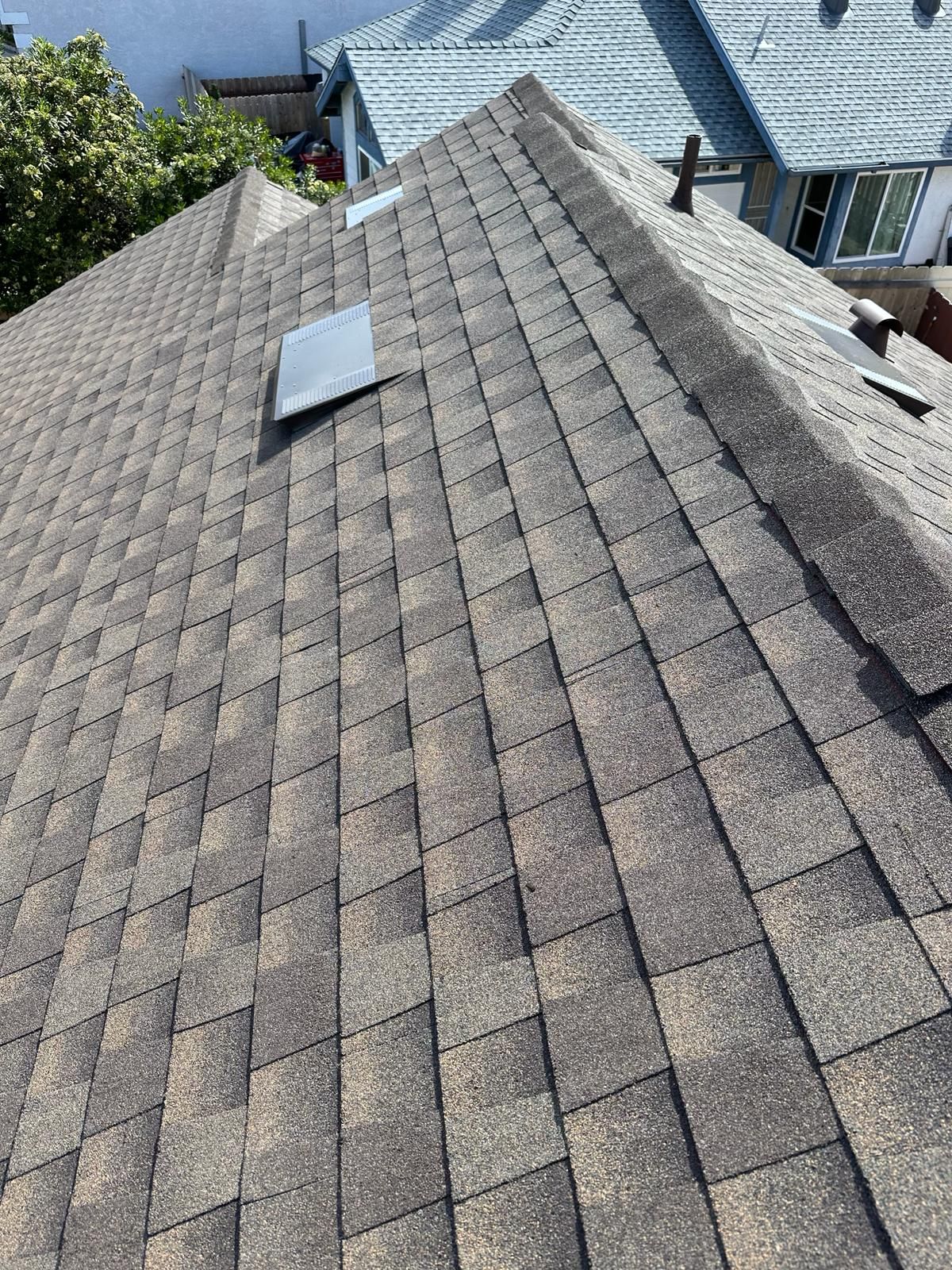 A close up of a roof with shingles and a skylight.