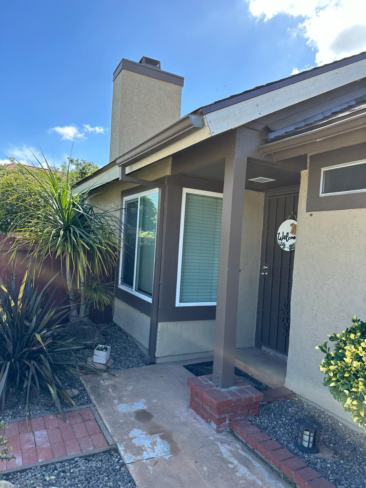 The front of a house with a porch and a chimney.