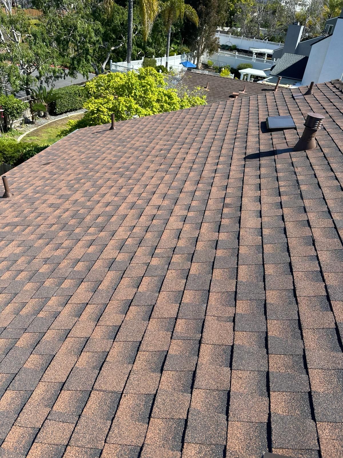 A close up of a roof with shingles and a skylight.