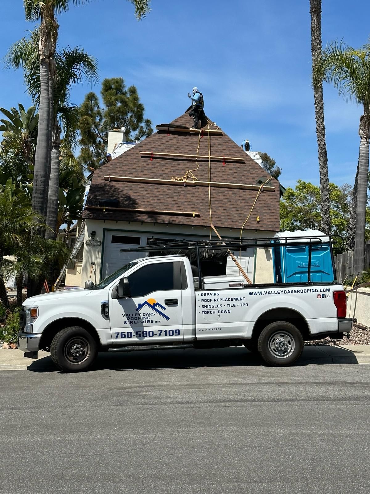 A white truck is parked in front of a house under construction.