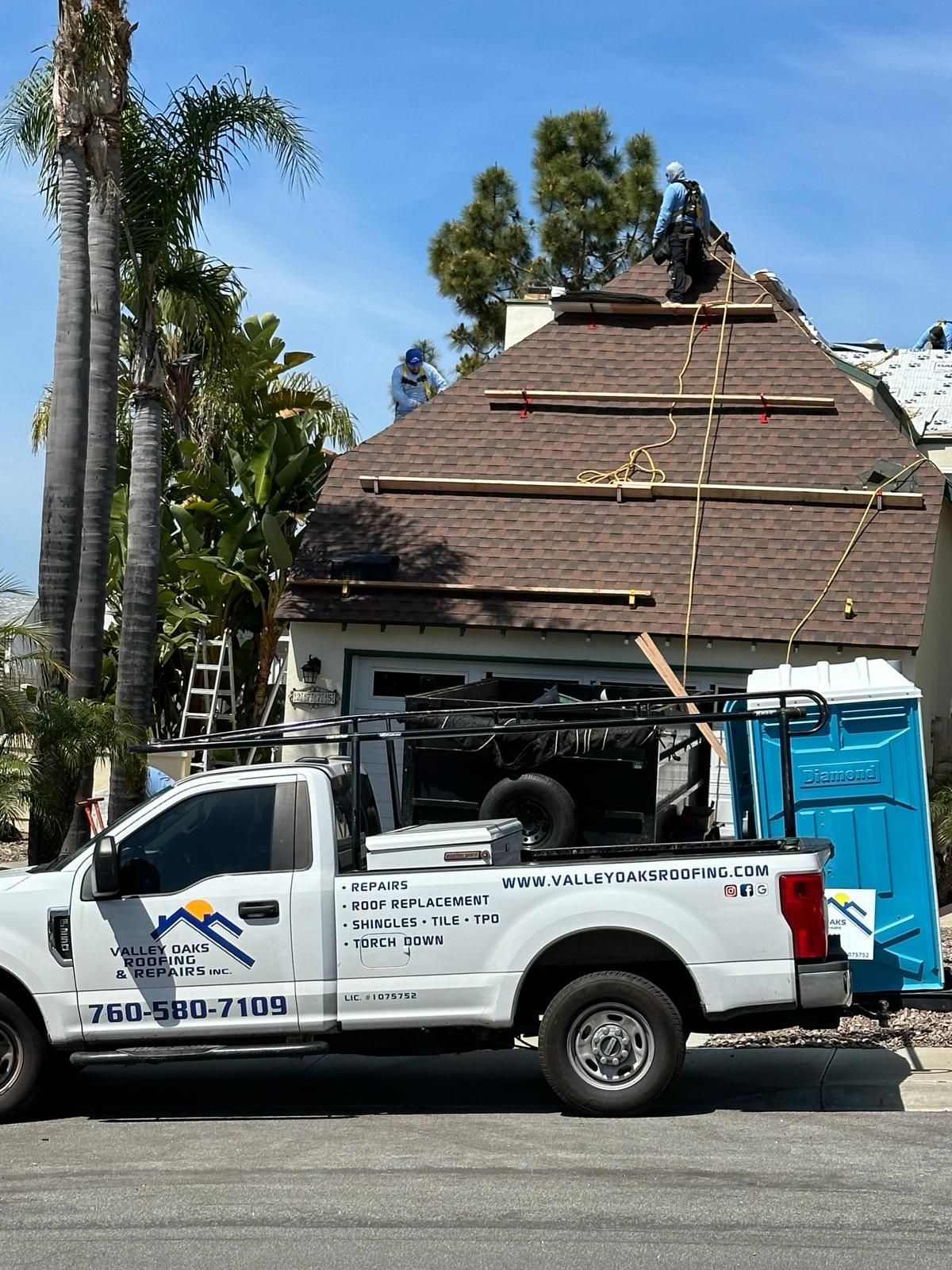 A white truck is parked in front of a house under construction.