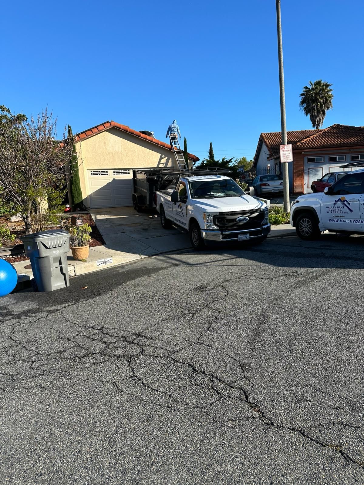 Two white trucks are parked in front of a house.