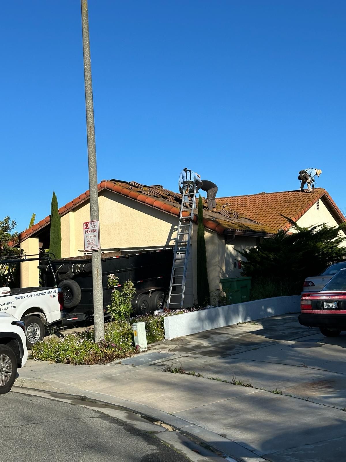 A man on a ladder is working on the roof of a house.