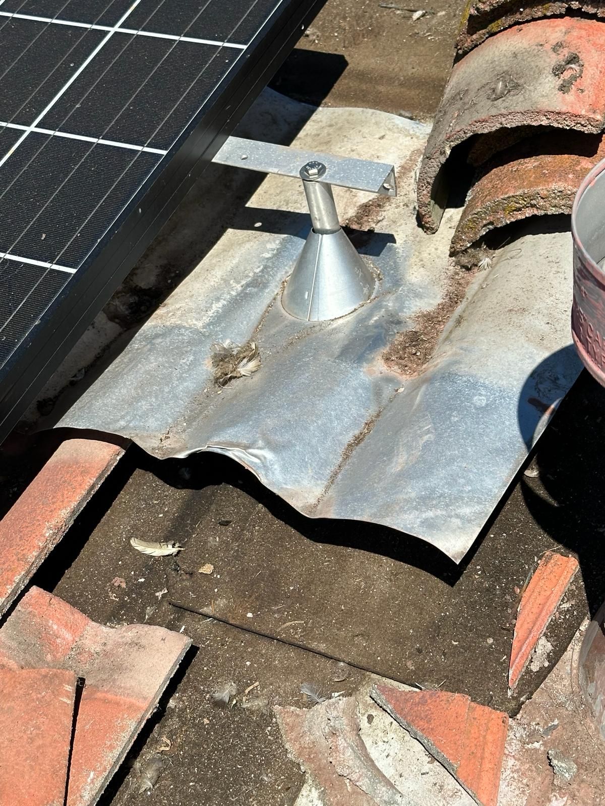 A solar panel is sitting on top of a tiled roof.