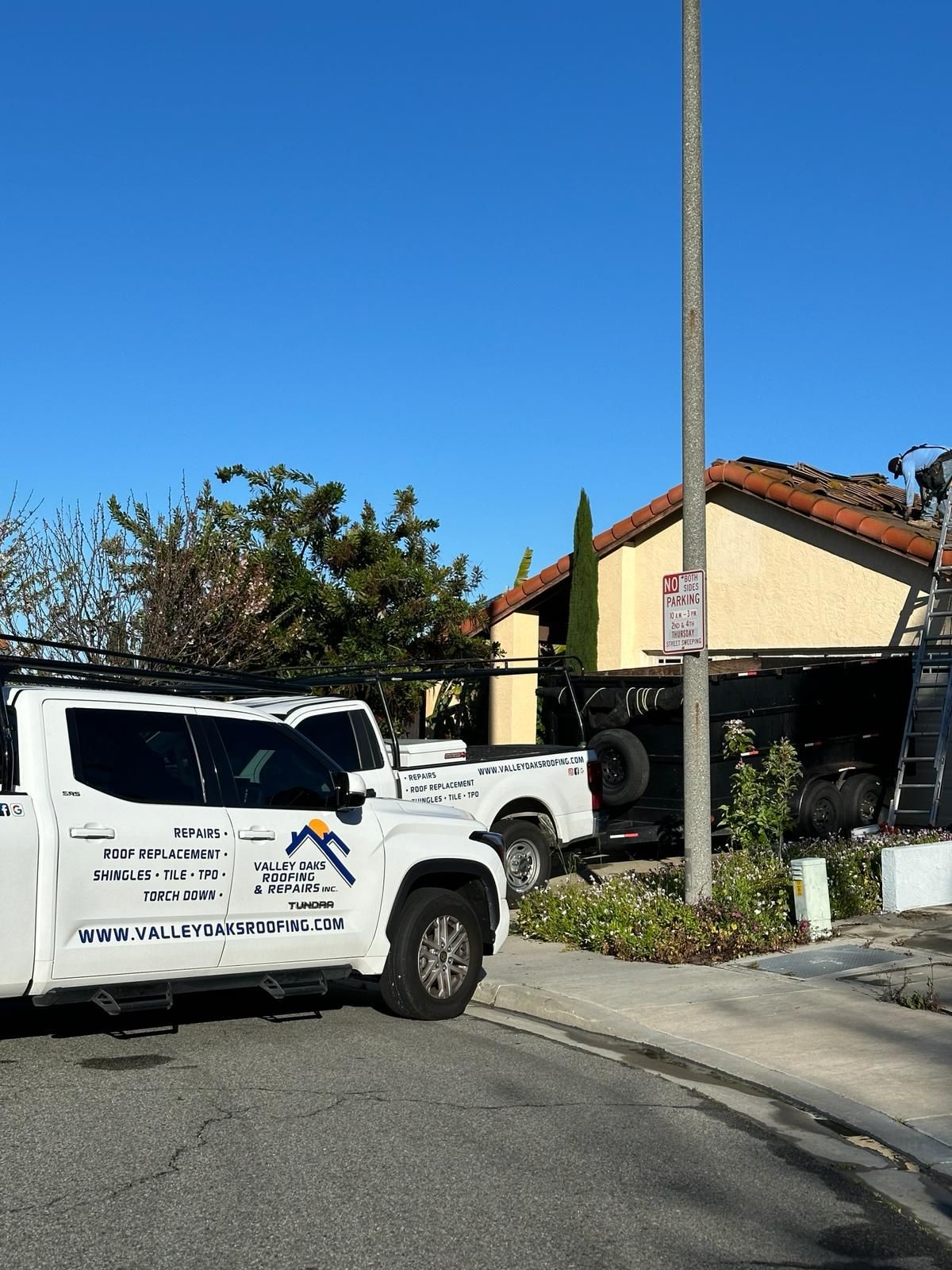 A white truck is parked on the side of the road in front of a house.