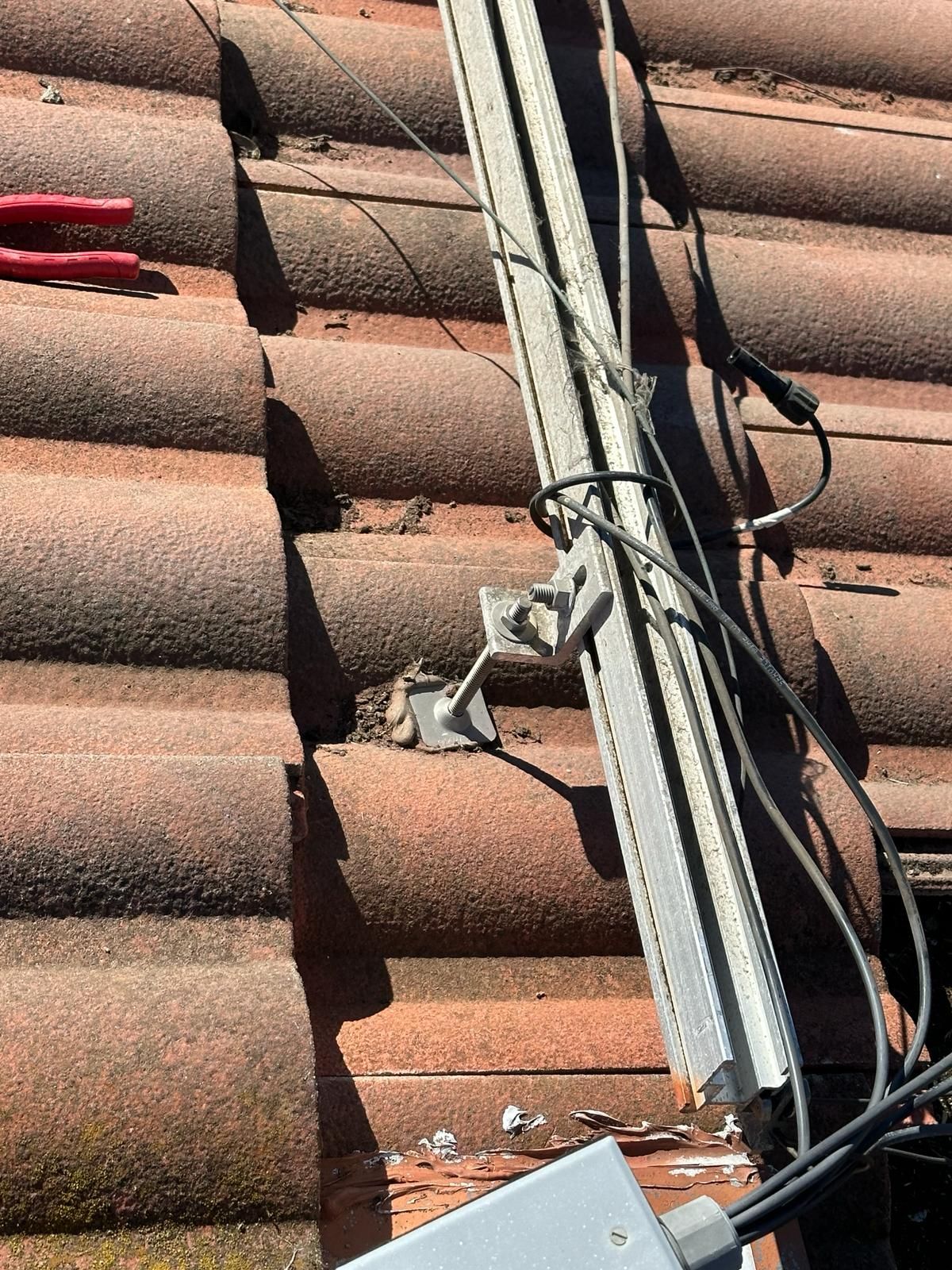 A roof with a lot of wires hanging from it and a pair of pliers.
