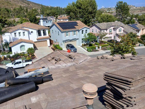 An aerial view of a residential neighborhood with a roof in the foreground.