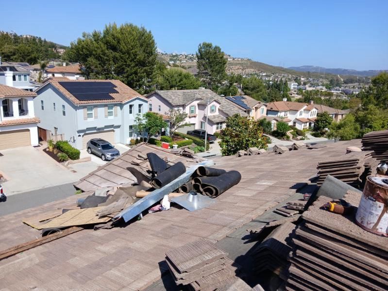 A roof with a lot of shingles on it is being repaired in a residential area.