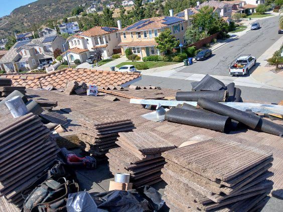 A pile of roofing materials is sitting on top of a roof in a residential area.