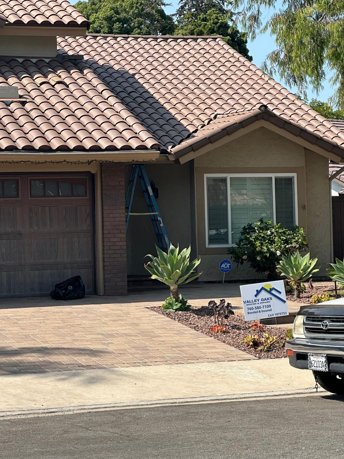 A truck is parked in front of a house with a tile roof.