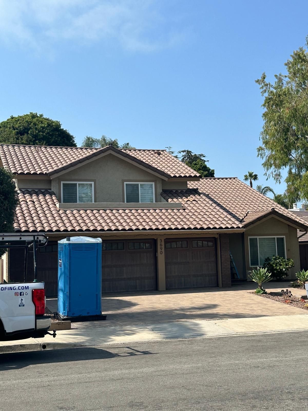 A blue portable toilet is parked in front of a house